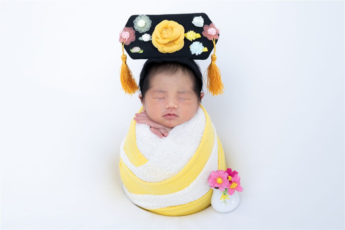 Newborn in a yellow wrap with a floral headdress